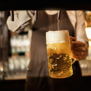 Close-up of bartender pouring draft beer in a glass.
