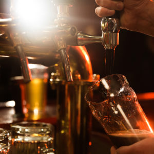 Close up of a bartender pouring beer while standing at the bar counter